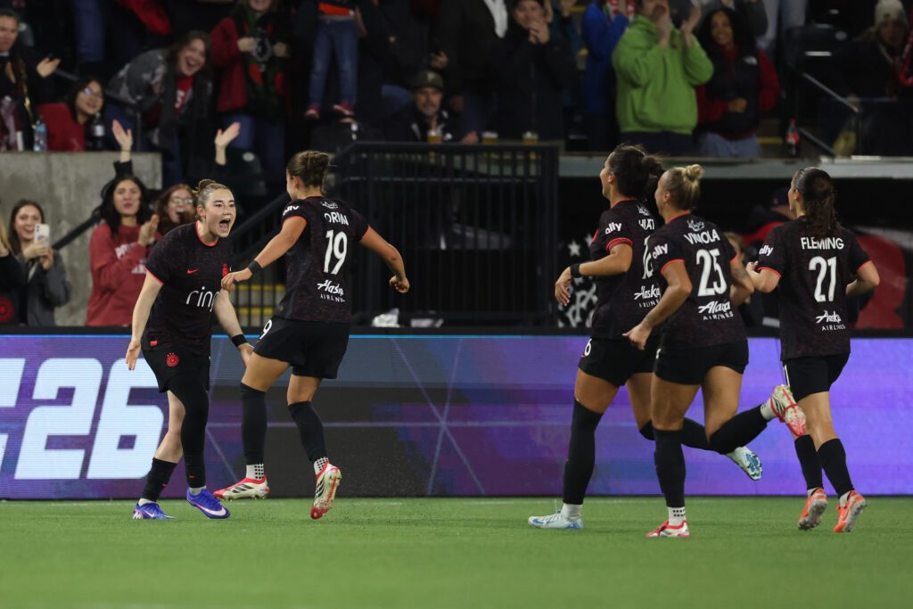 Portland Thorns forward Pietra Tordin celebrates her goal with midfielder Olivia Moultrie and other teammates during a 2026 NWSL match.