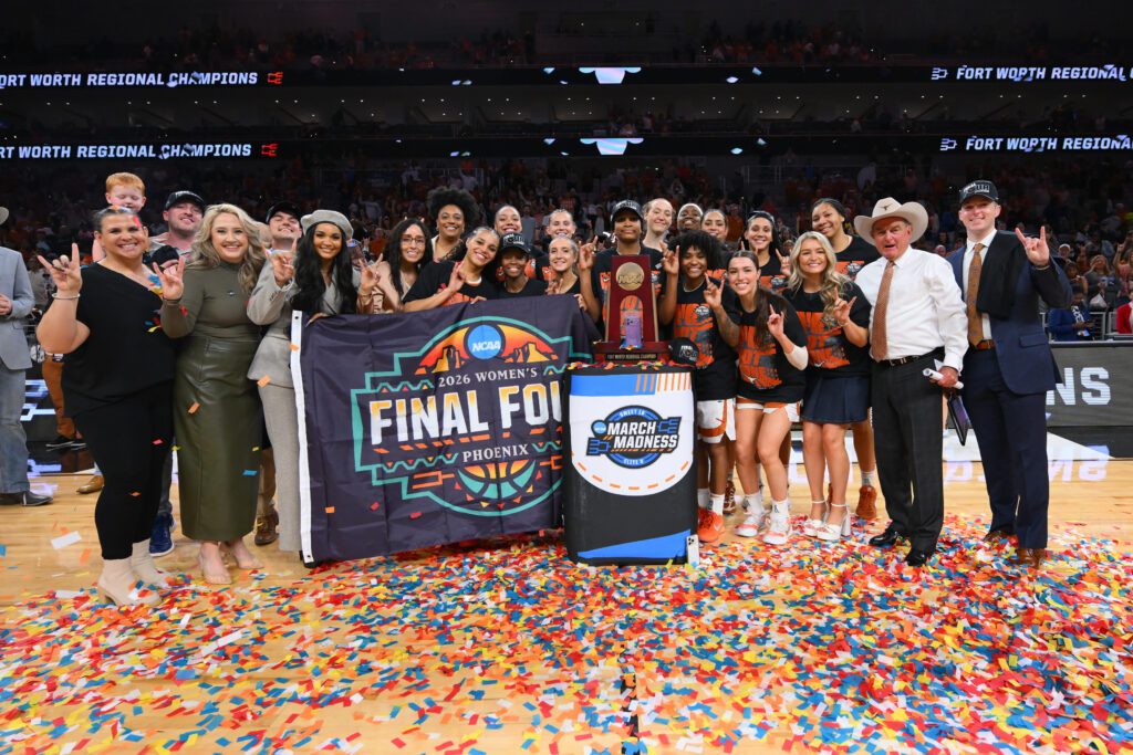 Texas women's basketball team and coaching staff pose with their 2026 March Madness Regional Championship trophy after their Elite Eight win.