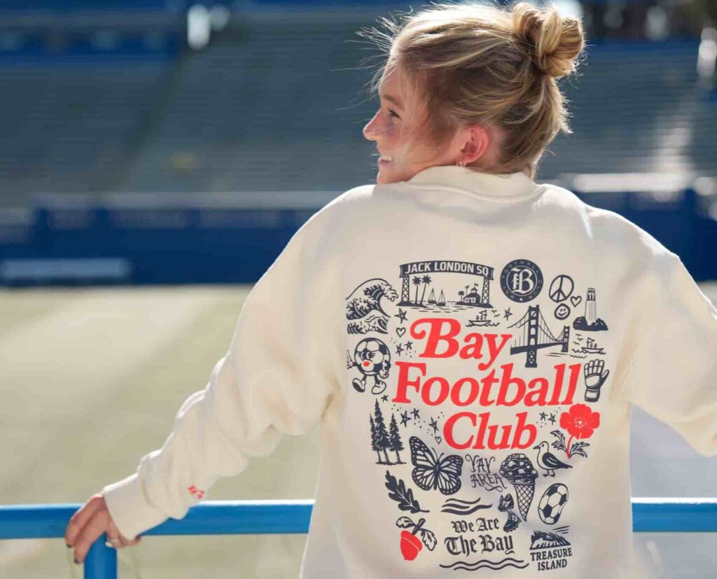 Bay FC player modeling Bay FC x Oaklandish sweatshirt at NWSL PayPal Park in San Jose.