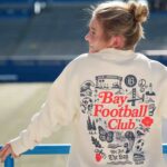 Bay FC player modeling Bay FC x Oaklandish sweatshirt at NWSL PayPal Park in San Jose.