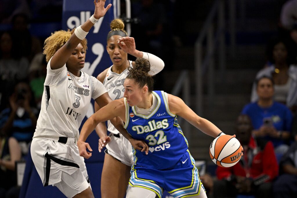 Dallas Wings forward Jessica Shepard (32) looks to move the ball past Las Vegas Aces forward Nalyssa Smith (3) and center A'ja Wilson (22) during the second half of the Aces vs Wings WNBA game at College Park Center.