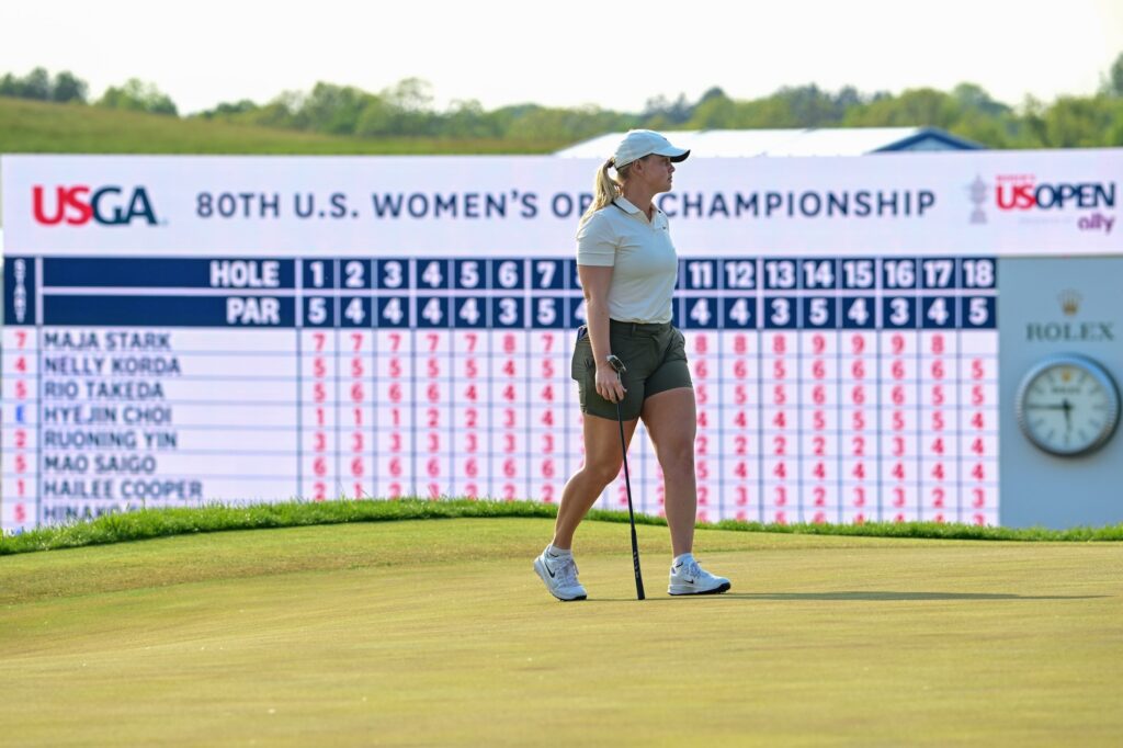 Maja Stark lines up a shot at the 18th green during the final round of the U.S. Women's Open golf tournament in front of the LPGA leaderboard featuring Nelly Korda.