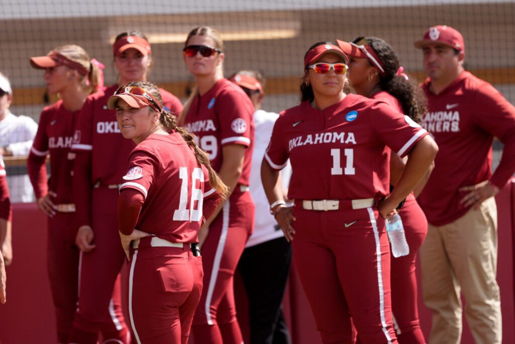 Oklahoma's Abby Dayton (16) and Kierston Deal (11) watch Mississippi State celebrate following Game 3 of the NCAA softball Norman Super Regional between the University of Oklahoma Sooners and the Mississippi State Bulldogs.