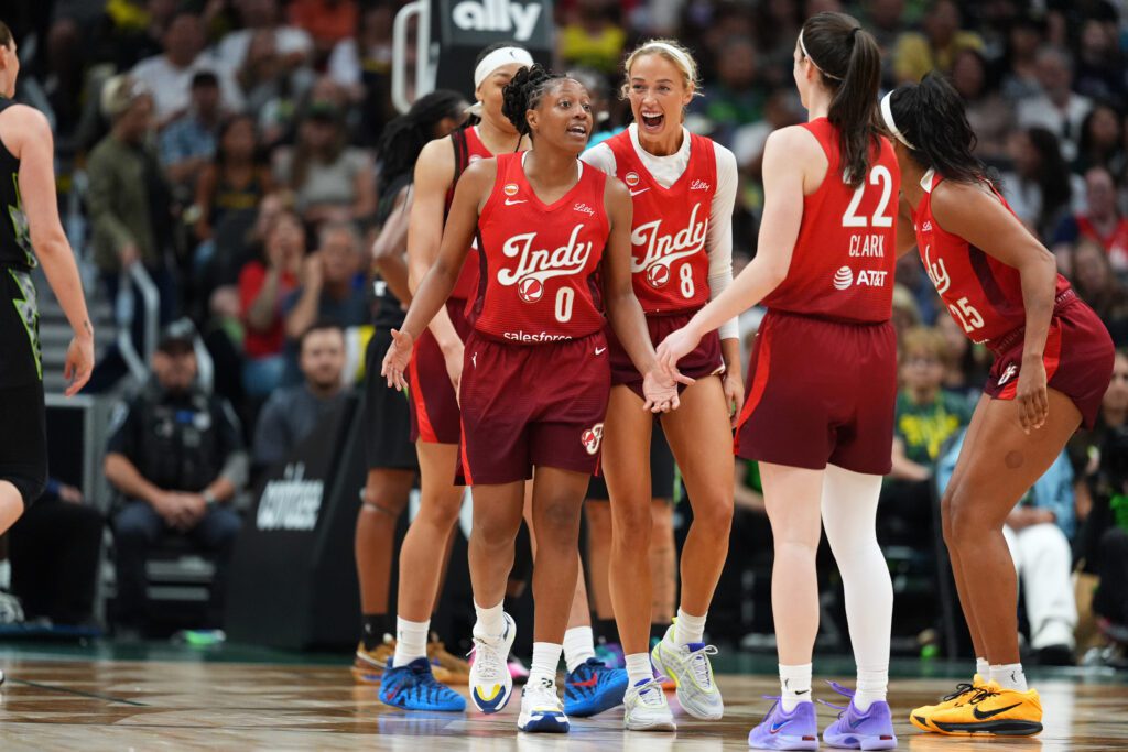 Kelsey Mitchell #0 of the Indiana Fever celebrates after making a basket and drawing a foul with teammates Sophie Cunningham #8, Caitlin Clark #22 and Monique Billings #25 during the second half against the Seattle Storm at Climate Pledge Arena.
