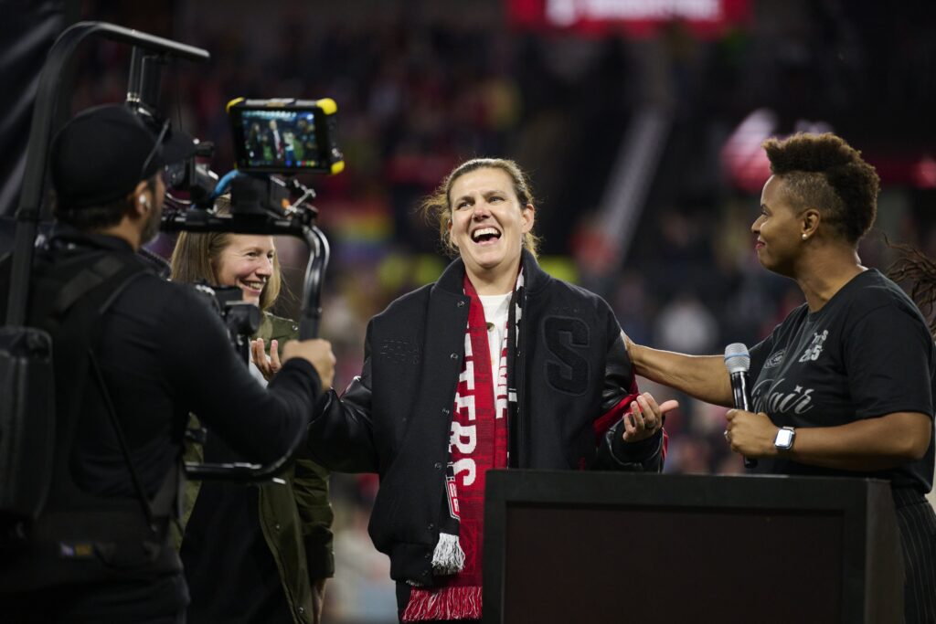 Retired Portland Thorns FC player women's soccer great Christine Sinclair receives a coat from former GM Karina LeBlanc, right, during a ceremony in her honor as she is inducted into the Thorns Hall of Fame at Providence Park.