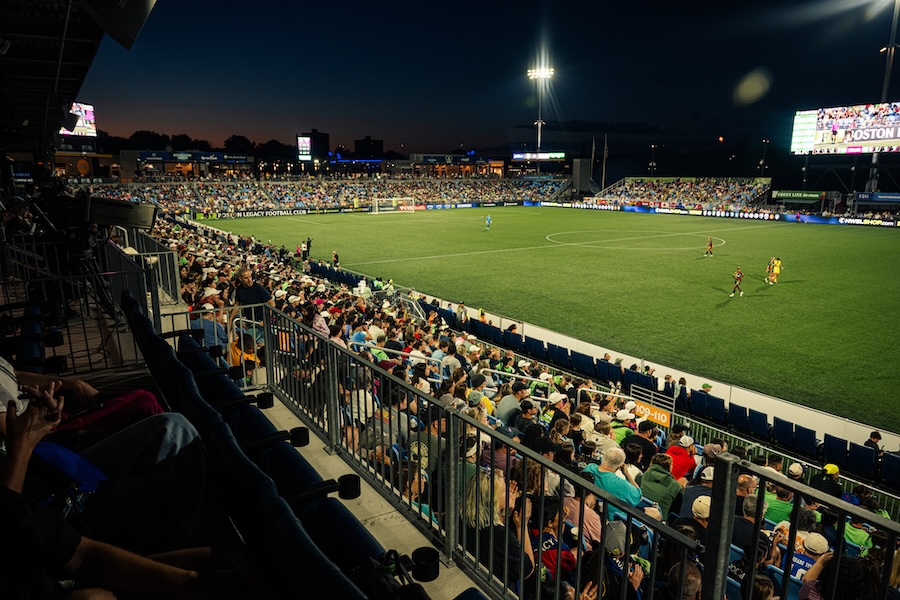 The Boston Legacy play an NWSL game at Centreville Bank Stadium in Rhode Island, in view of the stands and the scoreboard.