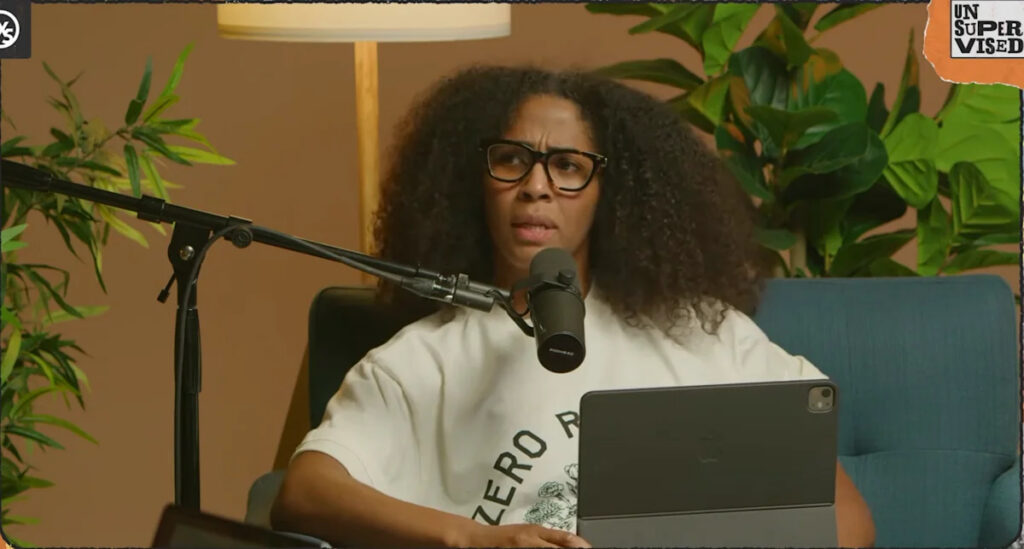 Former Indiana Fever player Sydney Colson records her podcast against a brown background holding an iPad.