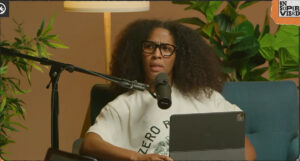 Former Indiana Fever player Sydney Colson records her podcast against a brown background holding an iPad.