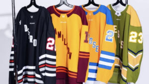 San Jose, Las Vegas, Detroit, and Hamilton PWHL jerseys hang alongside each other on a clothing rack.